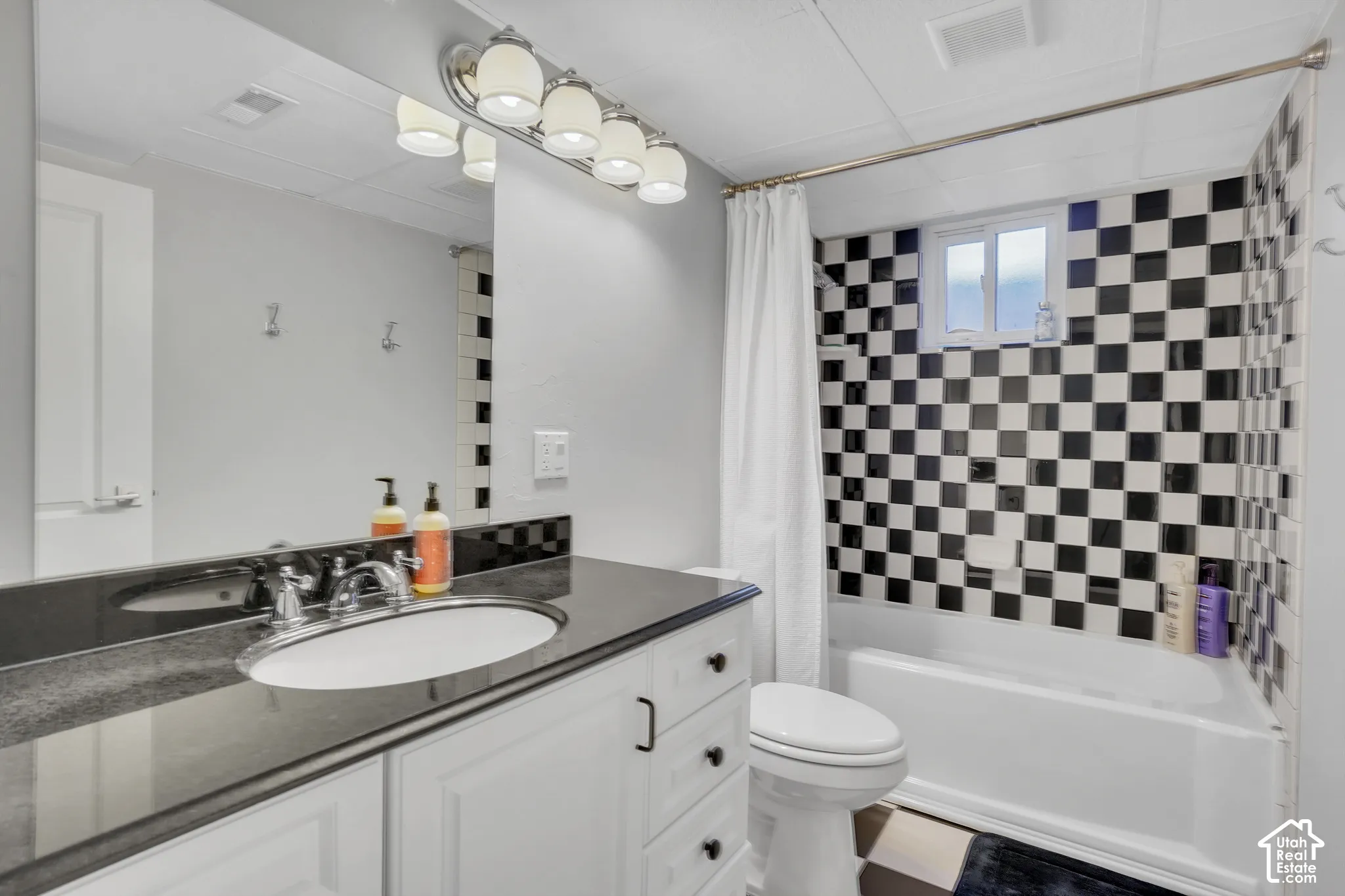 White shaker vanity with a dark countertop, undermount sink, and chrome faucet