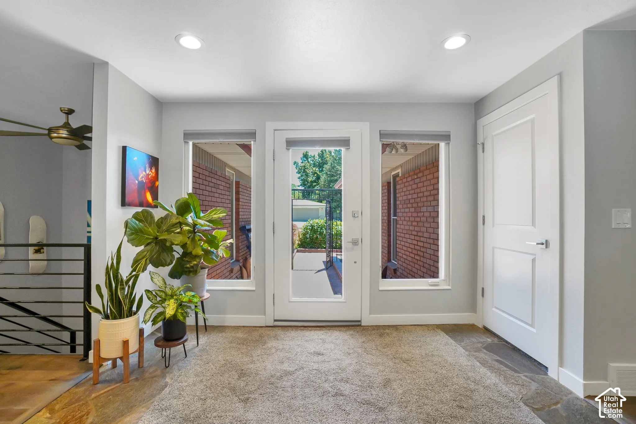 Recessed lighting illuminates the space, featuring a glass-paneled door flanked by two windows