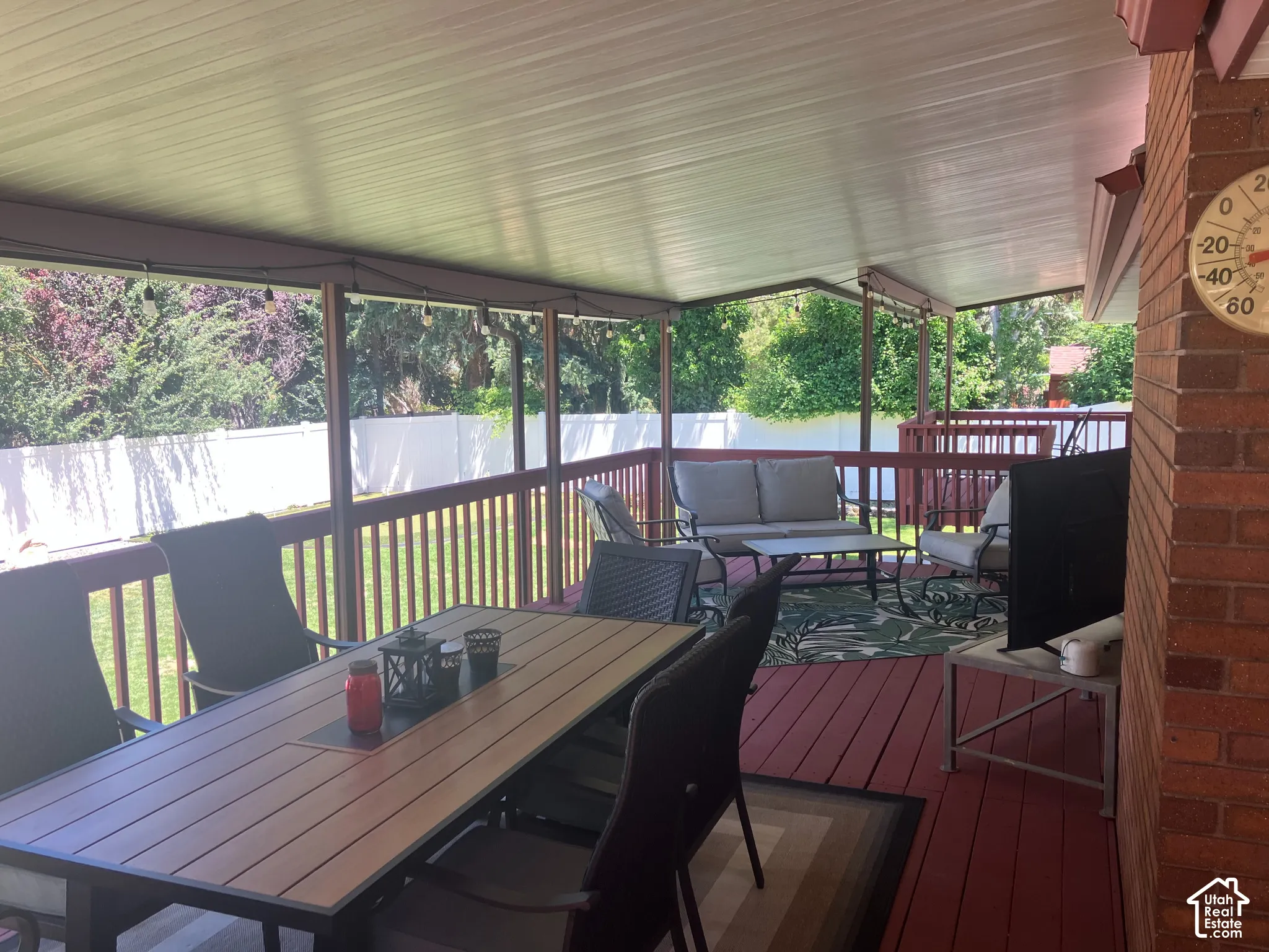 Covered deck with a solid overhead structure, rich red flooring, and a perimeter railing
