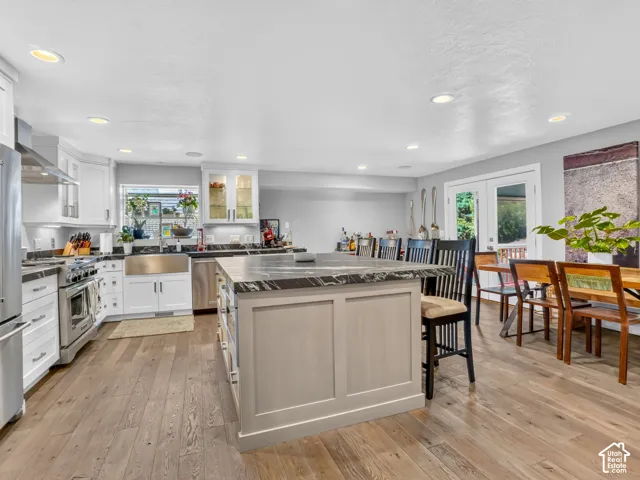 Spacious kitchen with a central island, stainless steel appliances, white cabinetry, and wood-finish flooring