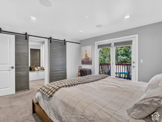 Recessed lighting, wood-finish barn doors, white trim, sliding glass door, and outdoor balcony with dark railing