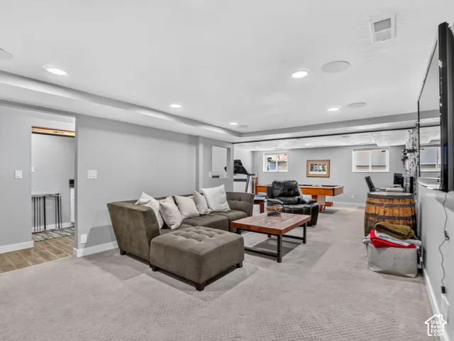 Recessed lighting, wall-mounted television, and light-toned carpet flooring