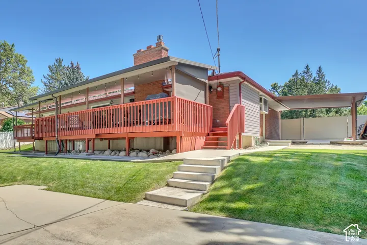 Expansive rear deck with red wood railings and a covered patio area