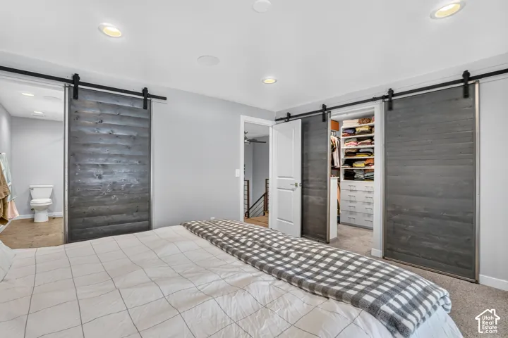 Recessed lighting, wood-finish barn doors, built-in closet organization, and light gray wall paint