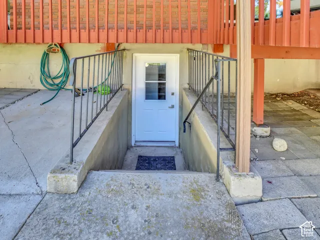 Concrete walkway with black metal handrails leading to a white entry door