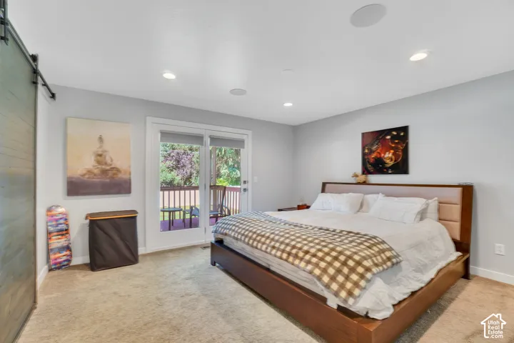 Barn door entry, recessed lighting, ceiling-mounted speakers, carpet flooring, and exterior balcony access