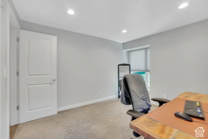 Recessed lighting, light gray wall paint, carpeting, white trim, and a window with a roller shade