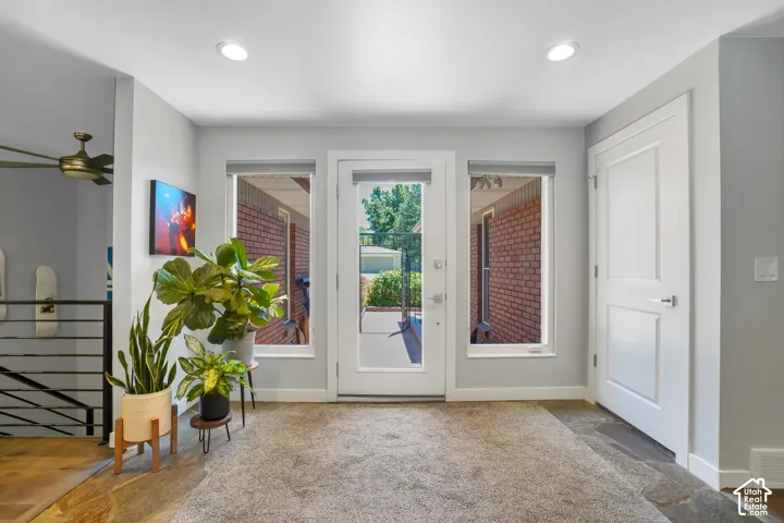 Recessed lighting illuminates the space, featuring a glass-paneled door flanked by two windows