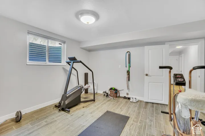 Recessed lighting, wood-finish flooring, white trim, and a white interior door