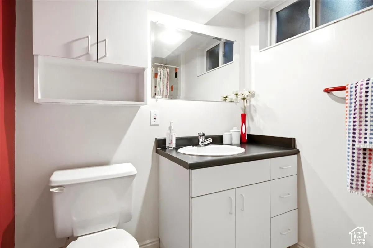 Vanity with integrated sink, dark countertop, and white cabinetry