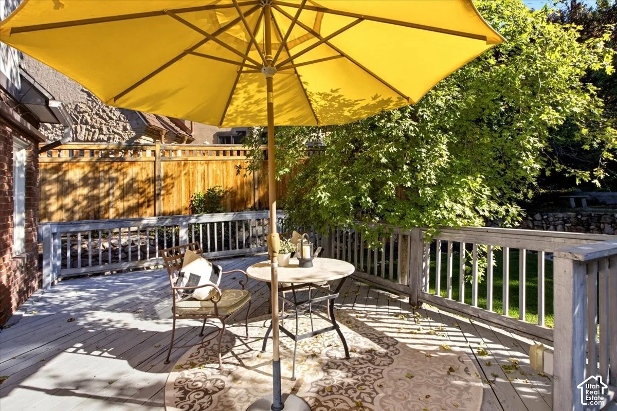 Spacious outdoor TREX deck with wood railing, brick exterior, and privacy fencing