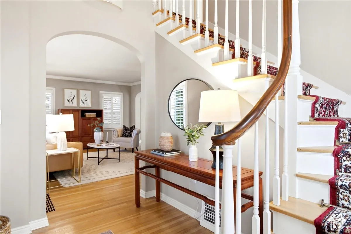 Hardwood flooring, arched doorway, and a staircase featuring a wood handrail with white balusters