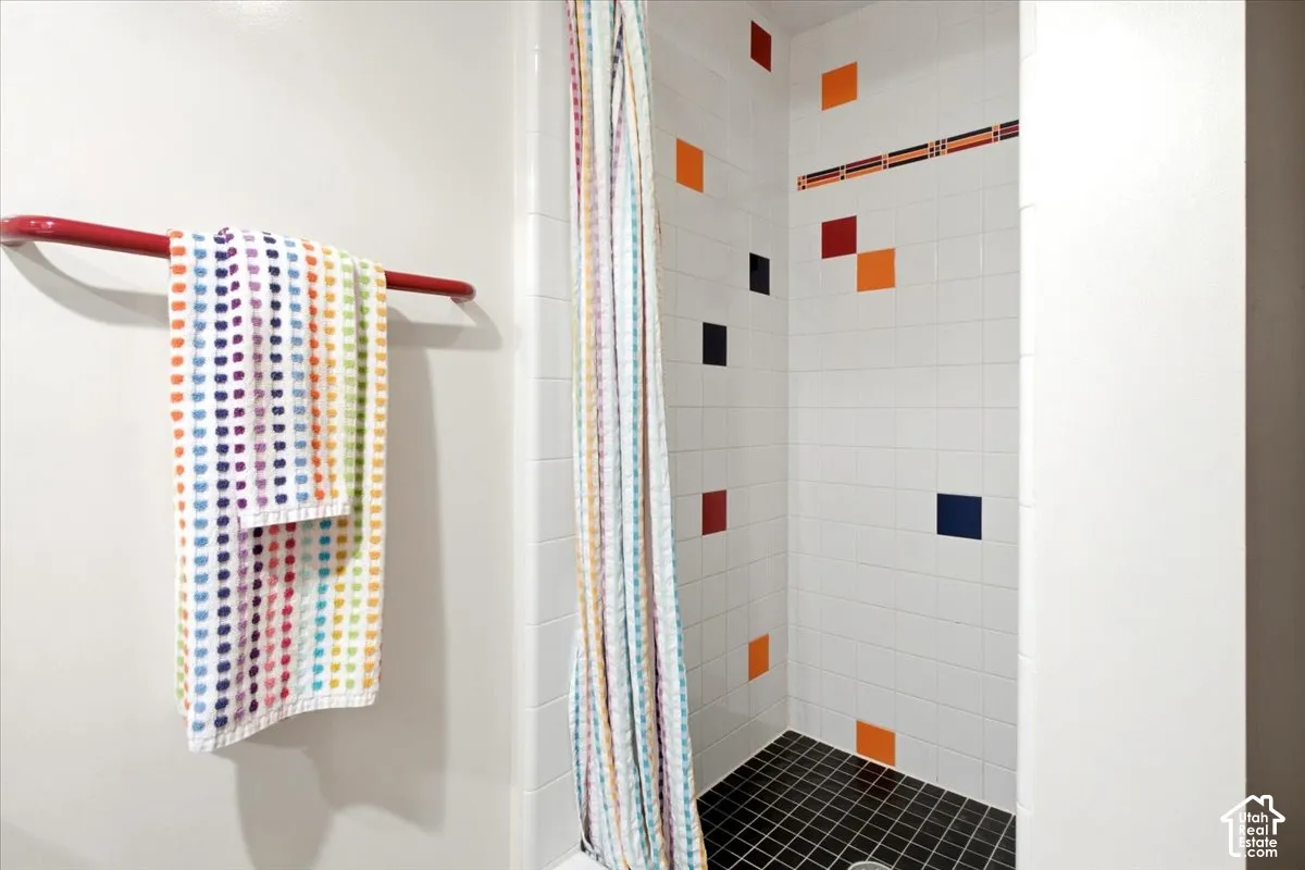 White tiled shower with contrasting black tile flooring and accent wall tiles
