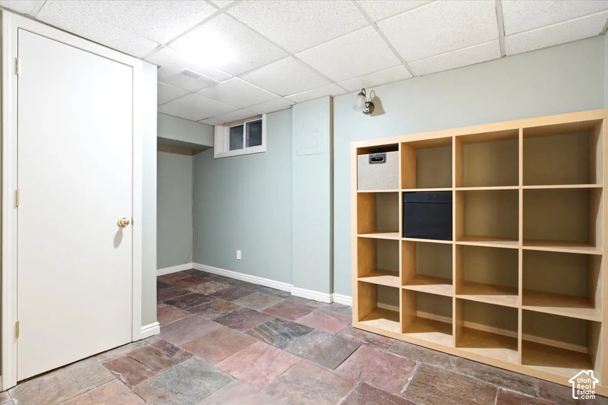 Slate flooring, recessed window, built-in shelving unit, drop ceiling, and wall-mounted lighting fixture