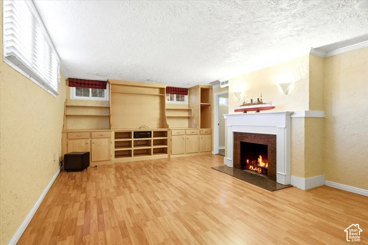 Hardwood-finish flooring, built-in entertainment center with shelving and overhead speakers for Dolby sound, recessed lighting, and a fireplace with a stone surround and white mantel