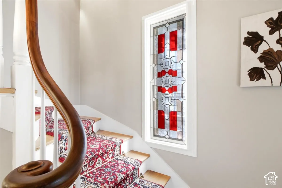 Stairs leading to second level with custom stained glass feature that stays with the home.