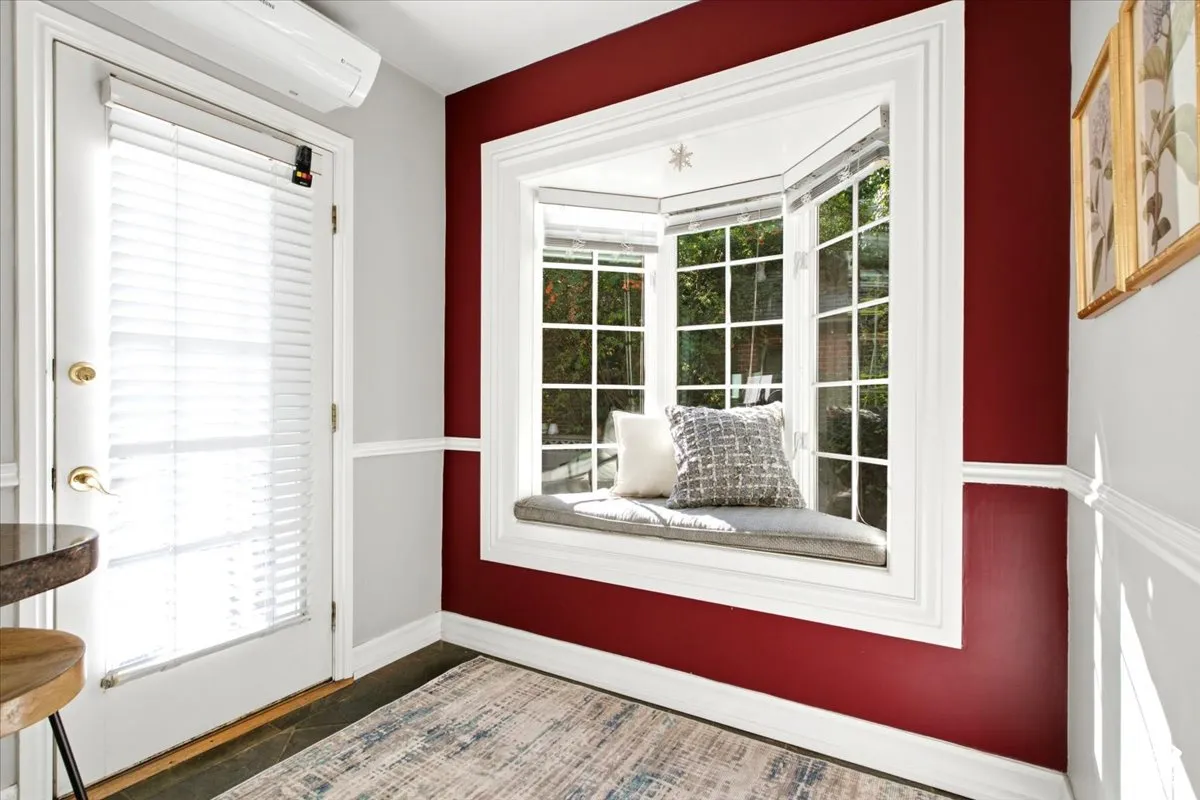 Bay window with a cushioned window seat, white trim, and a patio door with integrated blinds