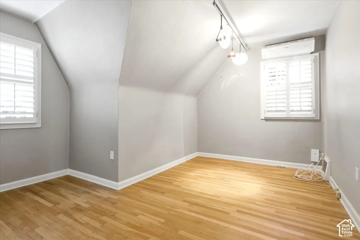 Hardwood flooring throughout, white plantation shutters, track lighting fixture, and a wall-mounted split