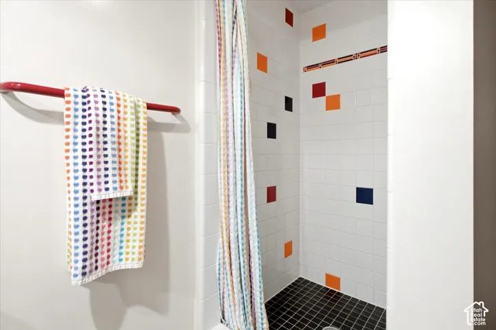 White tiled shower with contrasting black tile flooring and accent wall tiles