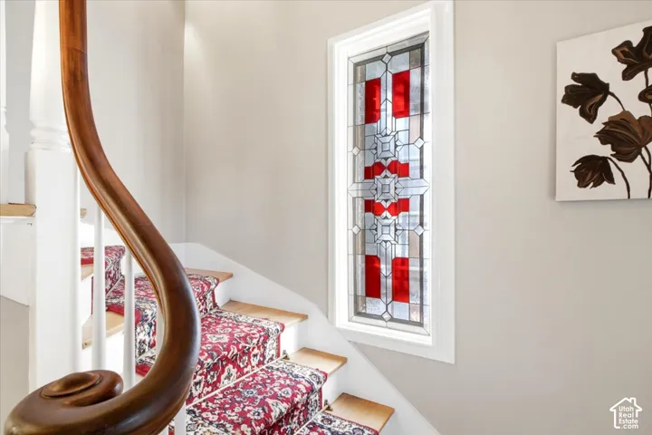 Stairs leading to second level with custom stained glass feature that stays with the home.