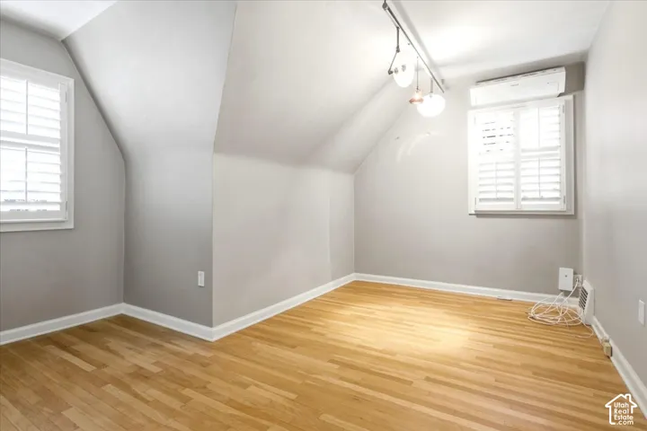 Hardwood flooring throughout, white plantation shutters, track lighting fixture, and a wall-mounted split