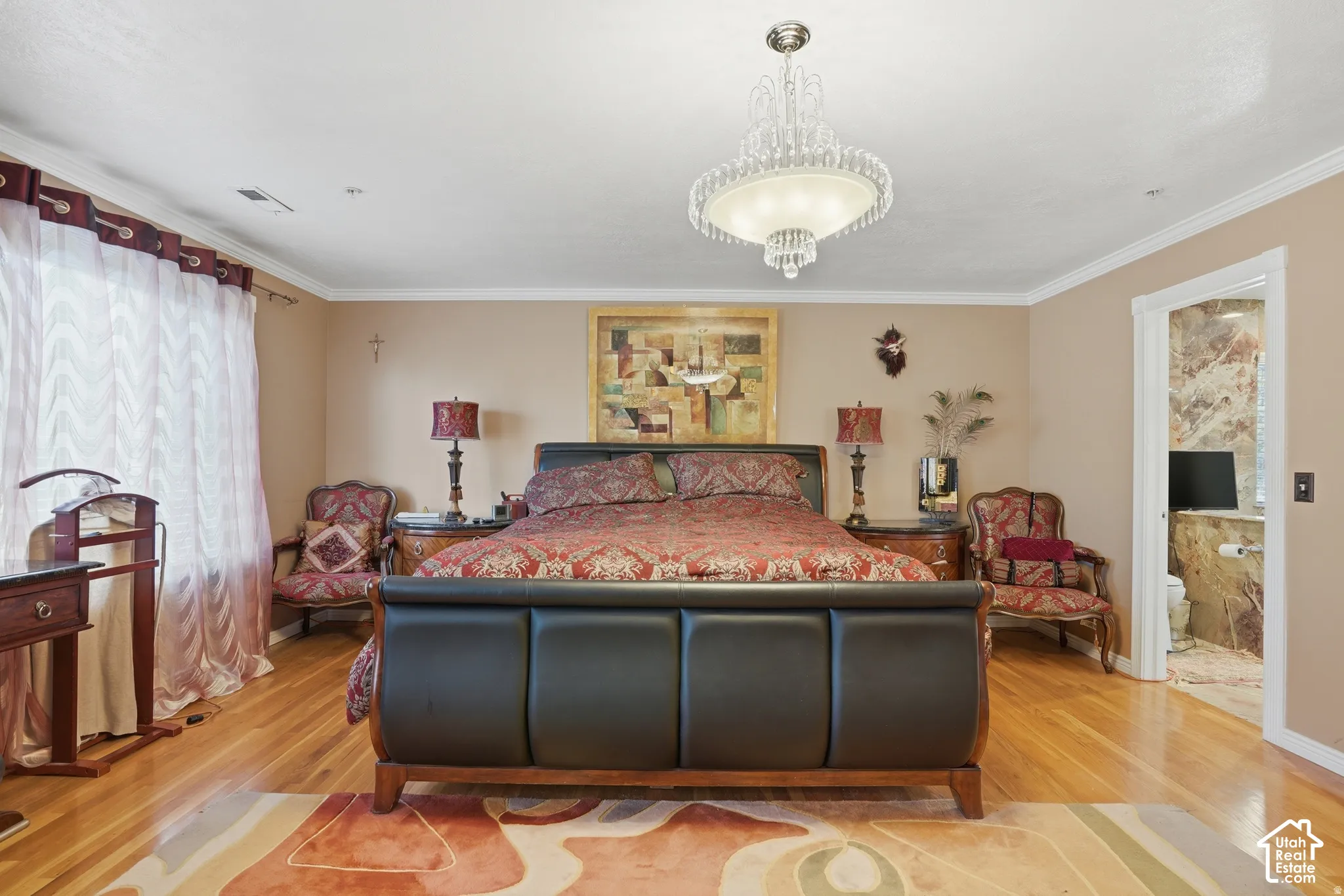 Polished wood-finish flooring, an ornate crystal chandelier, crown molding, and a built-in toilet nook with stone-finish walls