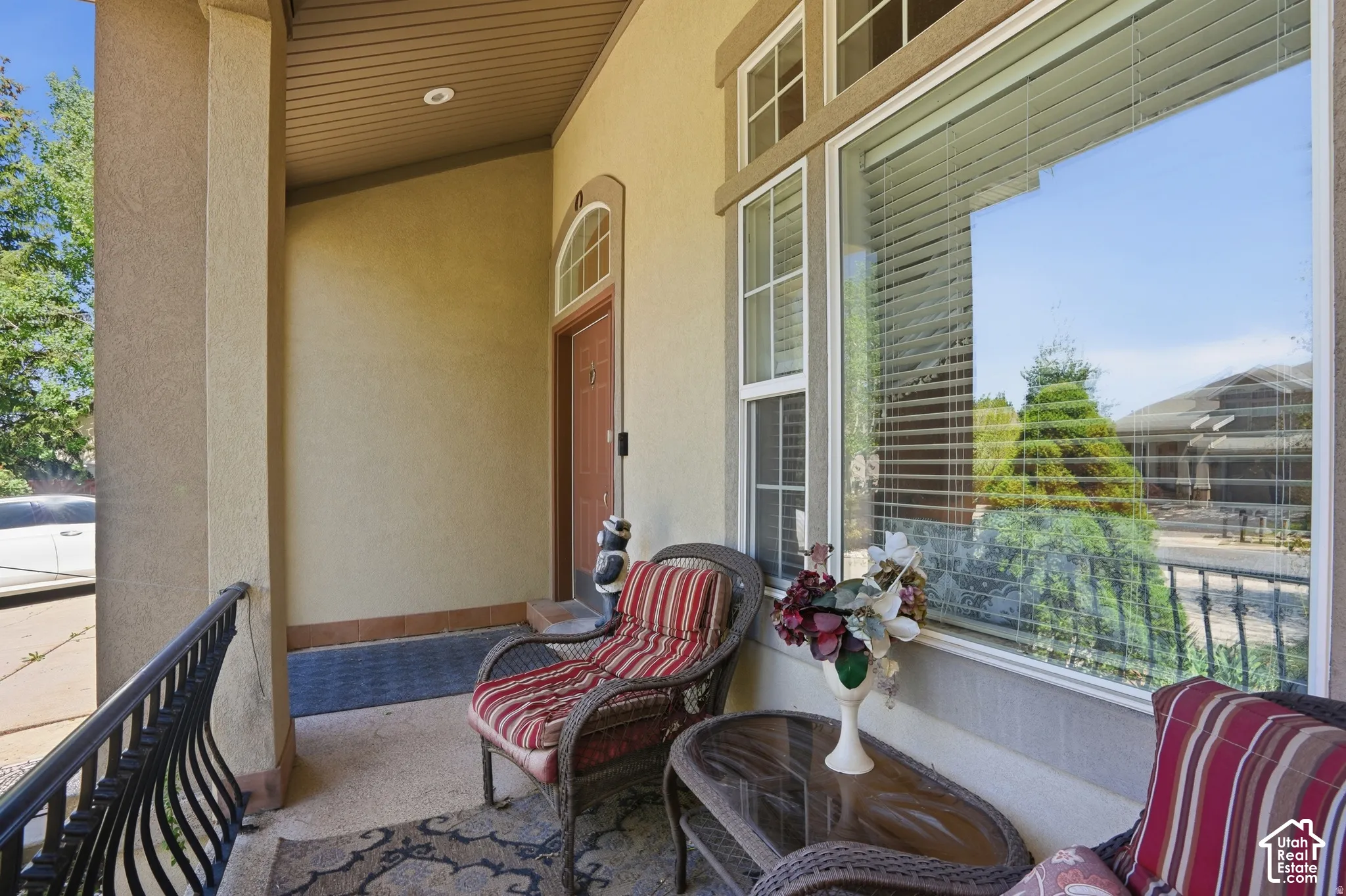 Covered entryway featuring a substantial pillar, wrought iron railing, and a window with transom details