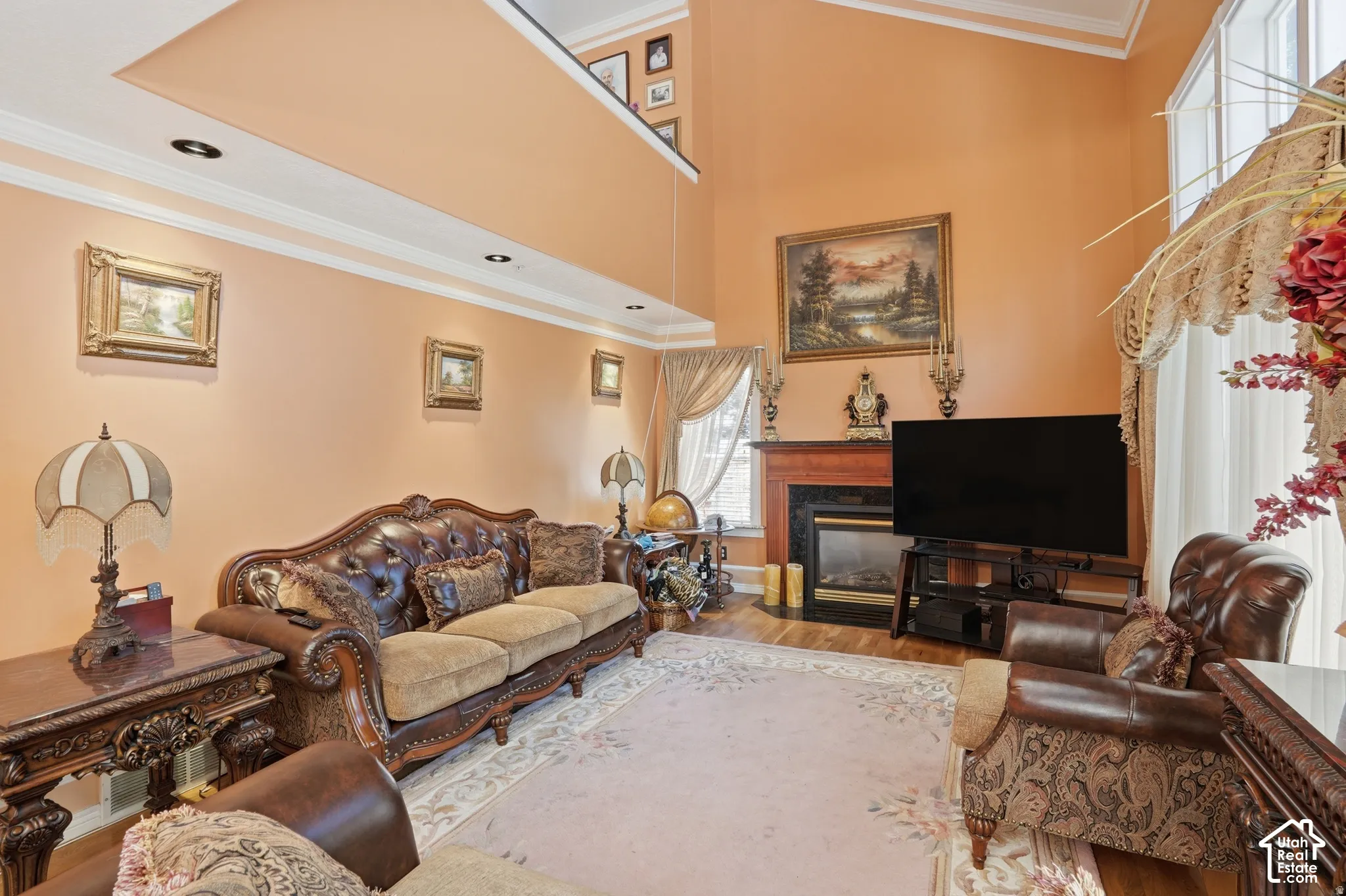 Two-story living area featuring a fireplace with a wood mantel, crown molding, and recessed lighting