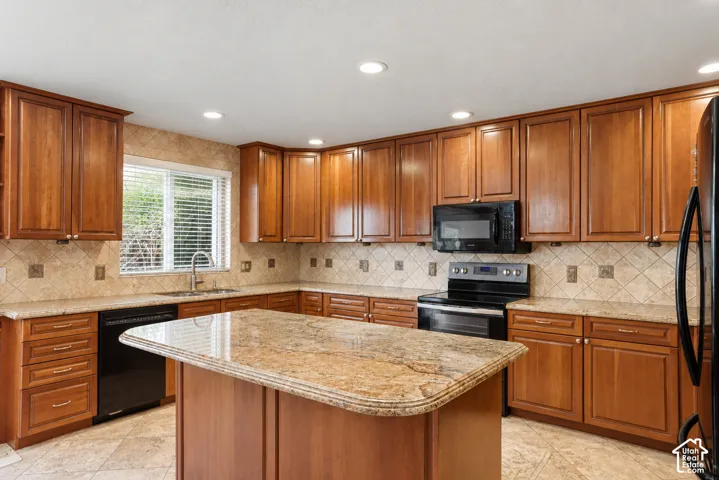 Kitchen featuring recessed lighting, extensive wood cabinetry, an integrated island, stone countertops, and a tiled backsplash