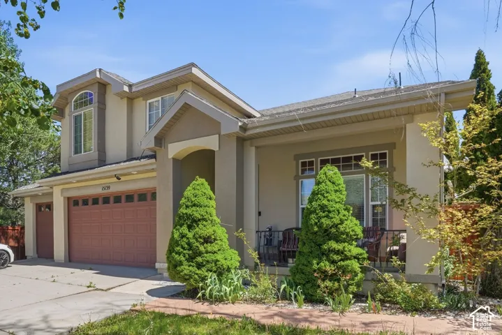 Stucco exterior with a covered porch, arched entry, and a two-car garage