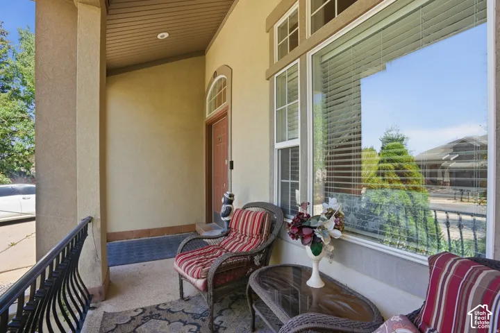 Covered entryway featuring a substantial pillar, wrought iron railing, and a window with transom details