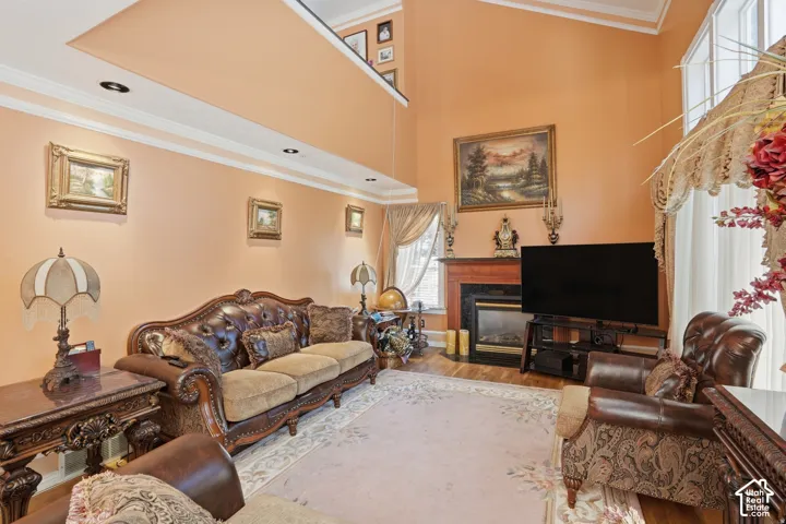 2-story great room featuring a fireplace with a wood mantle and surround, tall windows, crown molding, and recessed lighting