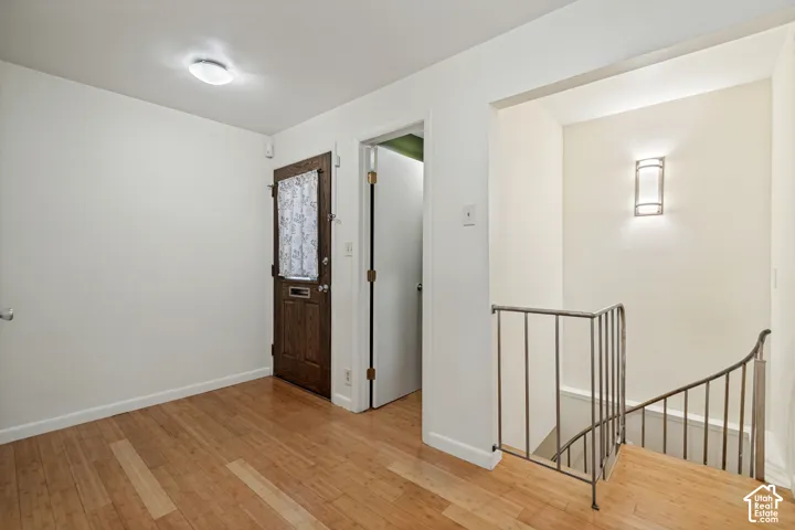 Wood-finish flooring, dark wood entry door, and a curved metal staircase railing