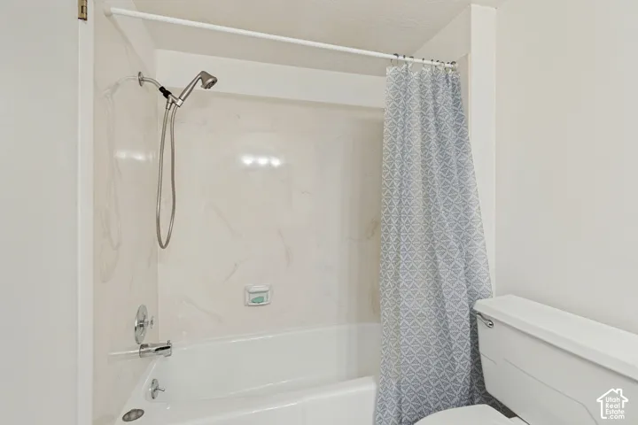 White bathtub with a built-in shower, complete with chrome fixtures and a flexible shower head