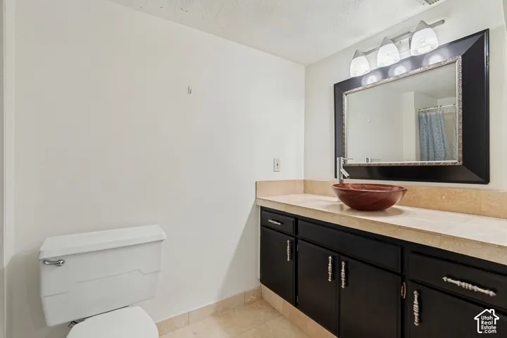 Vanity featuring a vessel sink, light-toned countertop, and dark cabinetry with decorative hardware