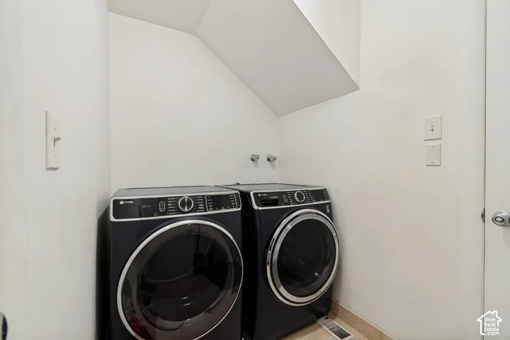 Laundry area with sloped ceiling and tile flooring