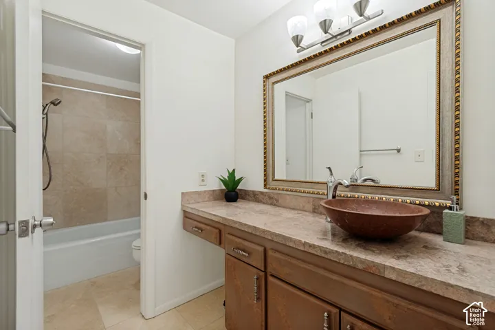 Bathroom featuring a vessel sink, single-handle faucet, vanity with cabinet storage, framed mirror, and tile flooring