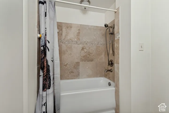 Bathtub with tiled surround, mosaic accent band, and a brushed nickel shower system
