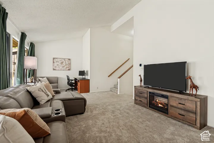 High ceilings with recessed lighting, light-toned carpeting, and a built-in media console with an electric fireplace