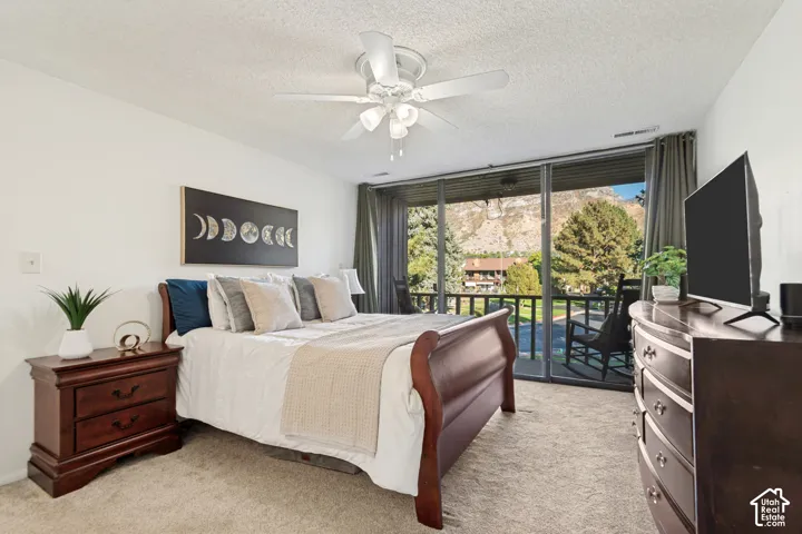Carpeted bedroom with a ceiling fan, sliding glass doors, and a mountain backdrop