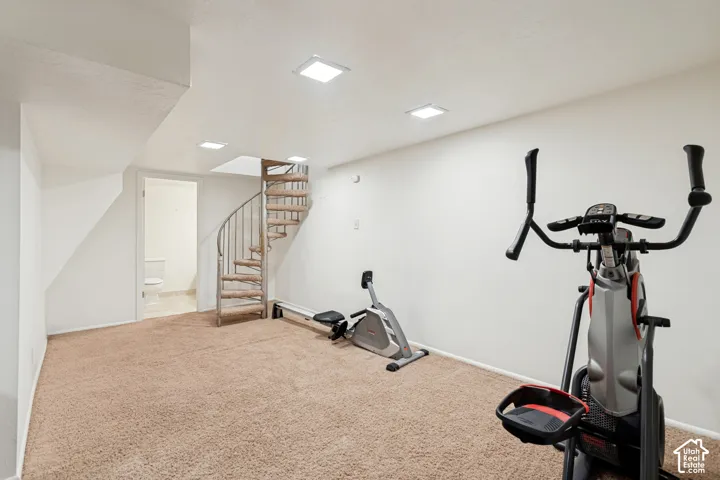 Spacious room featuring neutral carpeting, recessed lighting, white walls, and a spiral staircase