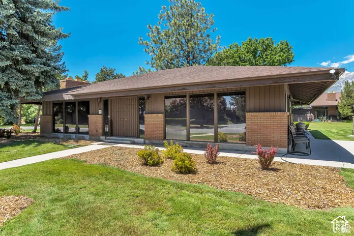 Mid-century modern residence featuring expansive windows, a covered entrance, a brick facade, and a concrete walkway