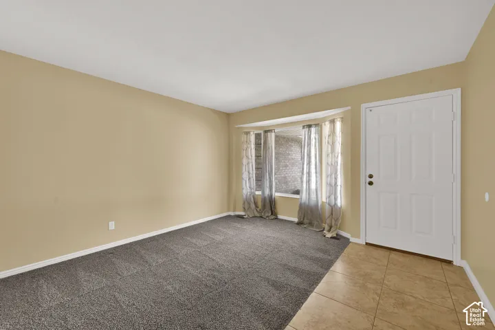 Room featuring a bay window, carpeted flooring, neutral wall paint, tile entry flooring, and a six-panel entry door