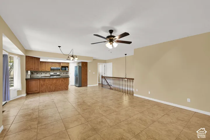 Kitchen featuring wooden cabinetry, tiled flooring, built-in breakfast bar, ceiling fan, and staircase with wooden balusters