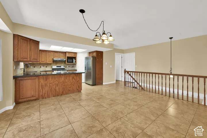 Kitchen featuring dark stone countertops, wood cabinetry, tile flooring, and a decorative wood railing