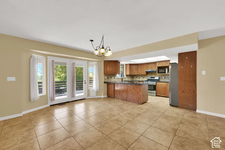 Open-concept kitchen and dining area featuring ceramic tile flooring, wood cabinetry, a central island, recessed lighting, and glass doors with exterior access