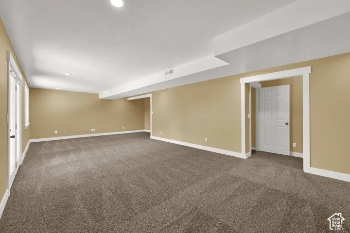 Expansive open-concept room featuring wall-to-wall carpeting, recessed ceiling lighting, crisp white door casings, and double glass doors