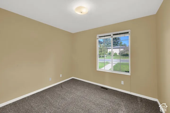 Neutral-toned interior room featuring wall-to-wall carpeting, a multi-pane window, and a flush-mount ceiling light fixture