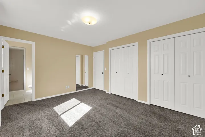 Neutral-toned walls, wall-to-wall carpeting, flush-mount ceiling lighting, two sets of white bi-fold closet doors, and an integrated full-length wall mirror