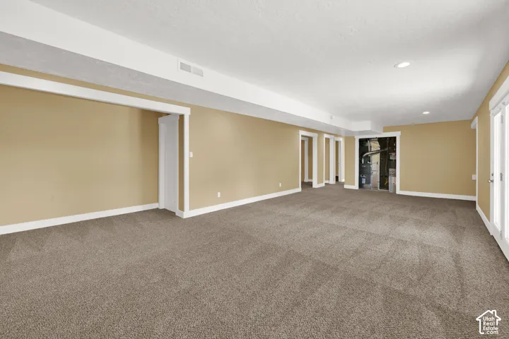 Open-concept interior space featuring wall-to-wall carpeting, recessed ceiling lighting, and multiple interior doorways